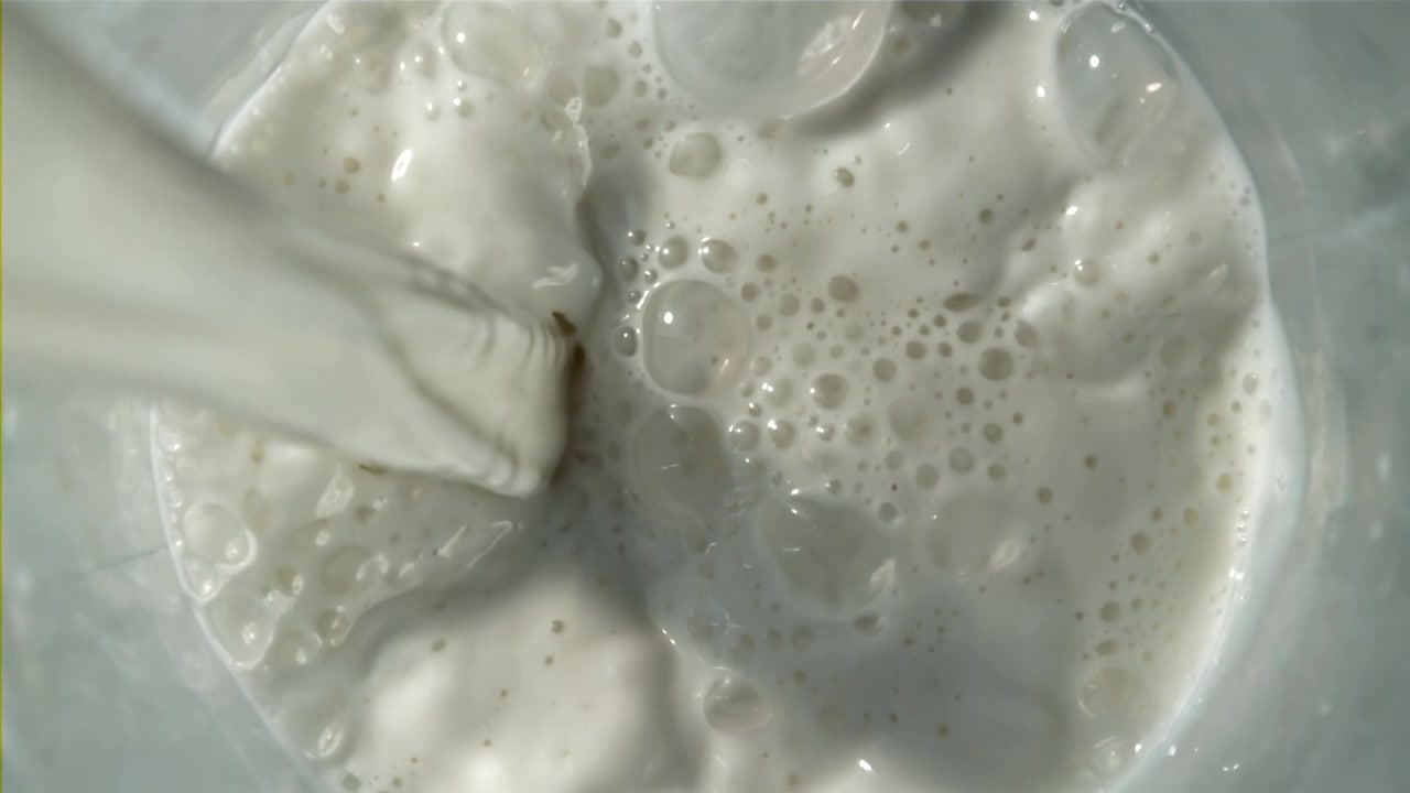 Versamento al rallentatore di latte bianco che crea bolle.
