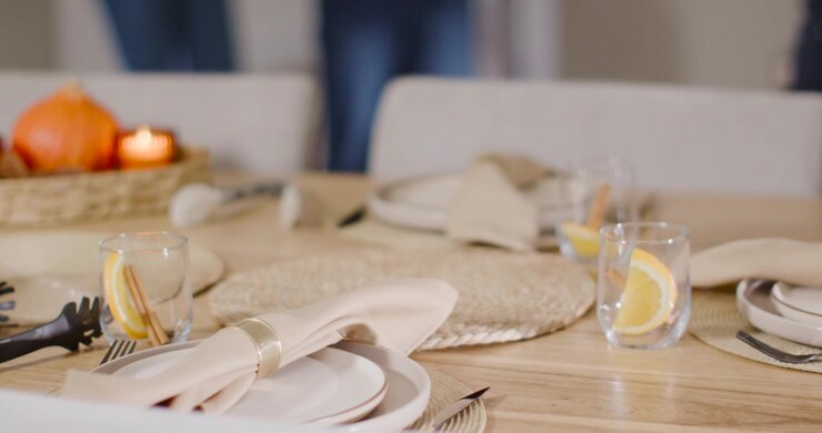 Elegante tavolo da pranzo in legno a fuoco, mentre figure sfocate entrano nell'inquadratura per sedersi, candele.