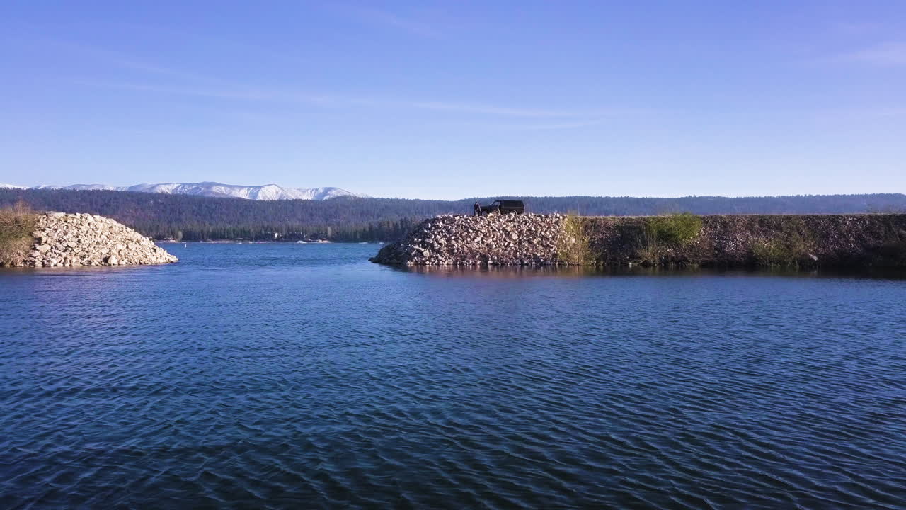 화창한 날, 공중에서 델라마 산맥의 호수 옆 제방에서 낚시하는 남자