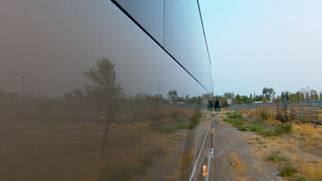 side view of a public bus, shuttle, or school bus driving and the road reflection on it