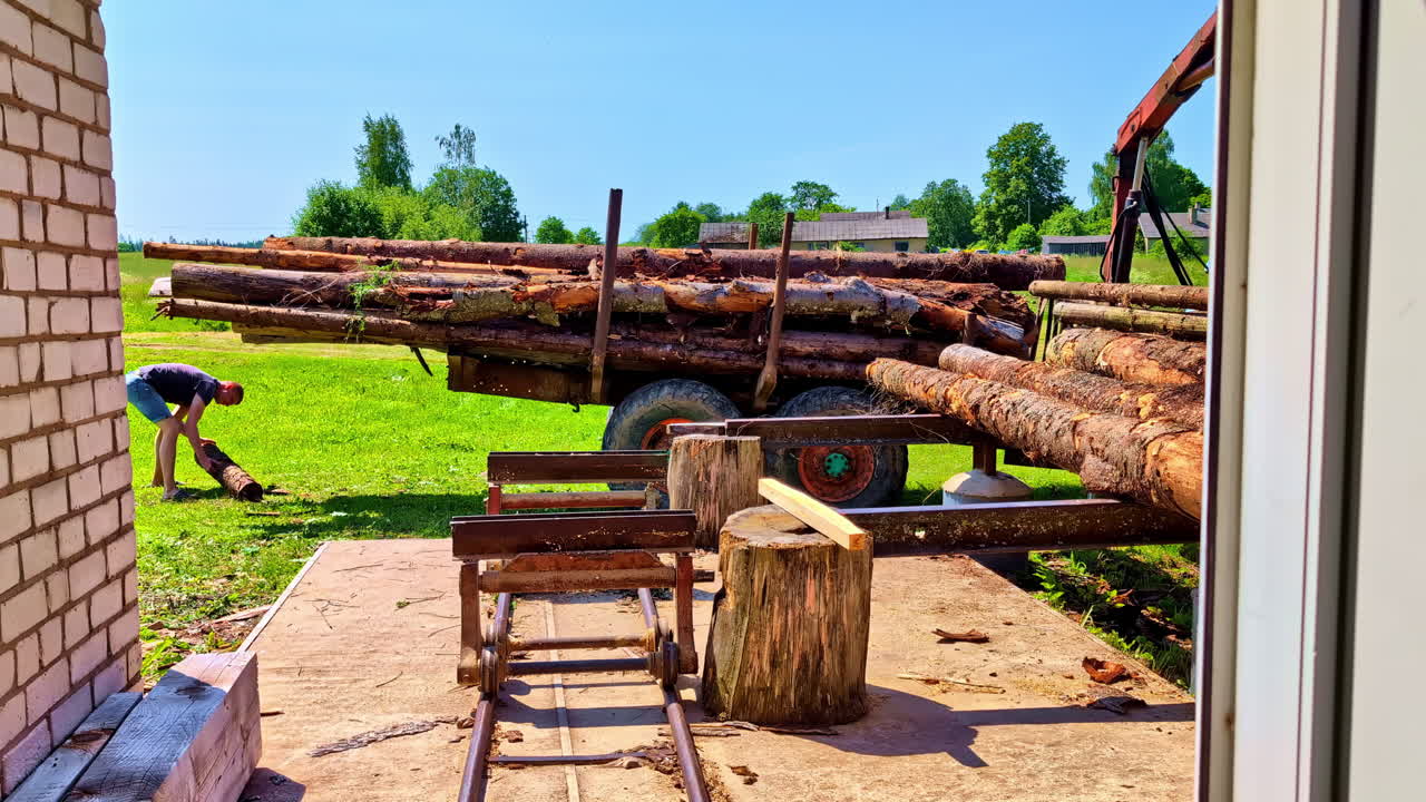 Log truck unloading timber from traictor trailer at rural sawmill site