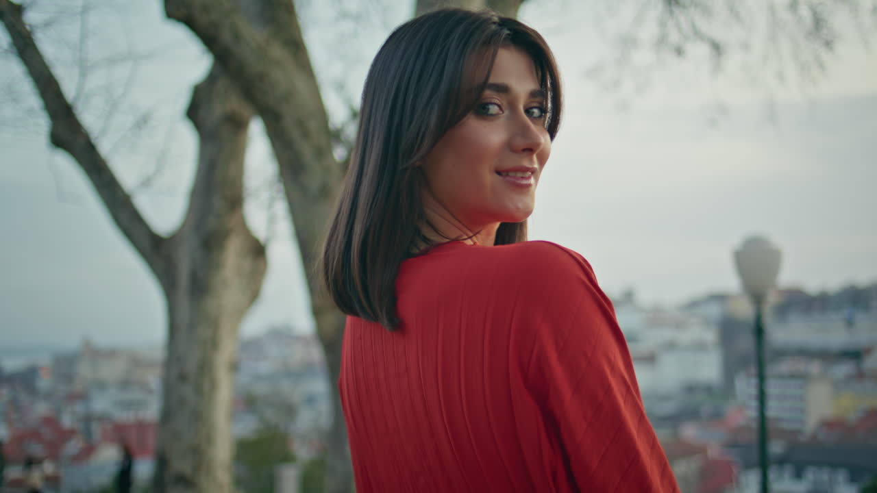 Brunette model adjusting hairstyle relaxing park back view. Woman turning camera