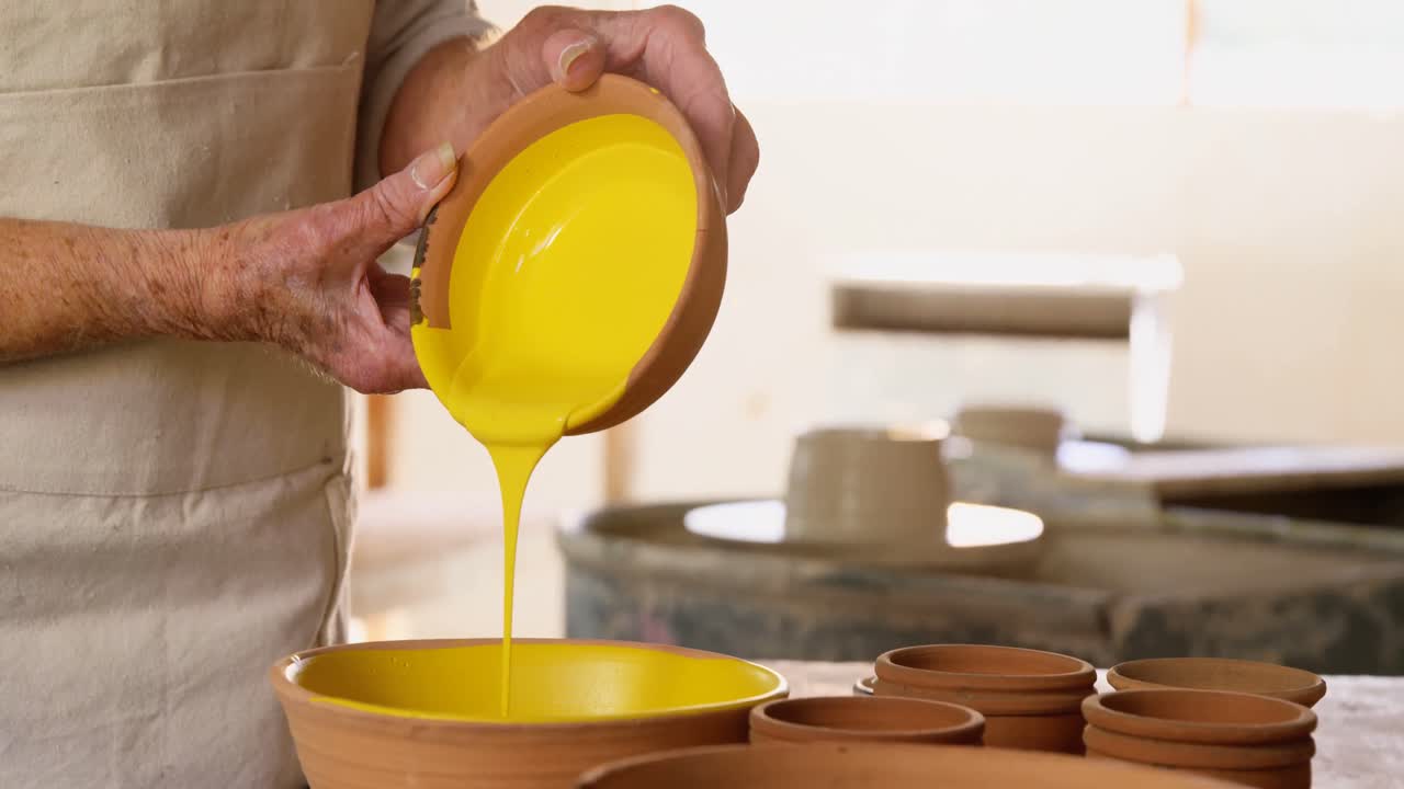sección media de la alfarera mujer vertiendo pintura en un cuenco