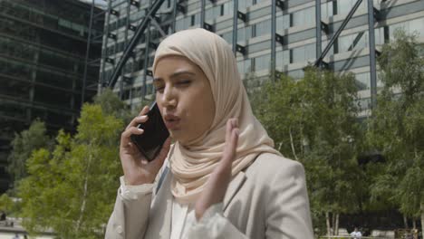 mujer de negocios musulmana en el teléfono móvil de pie fuera de la oficina en la ciudad 3