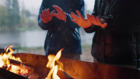 manos, cálidas y amigos con fuego en el campamento