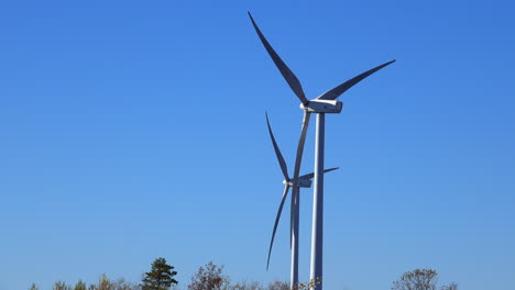 Rear-view-of-wind-turbines-operating-on-a-sunny,-clear-autumn-day