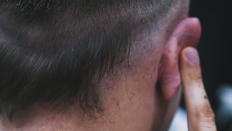 hairstylist shaves black hair on client head with machine