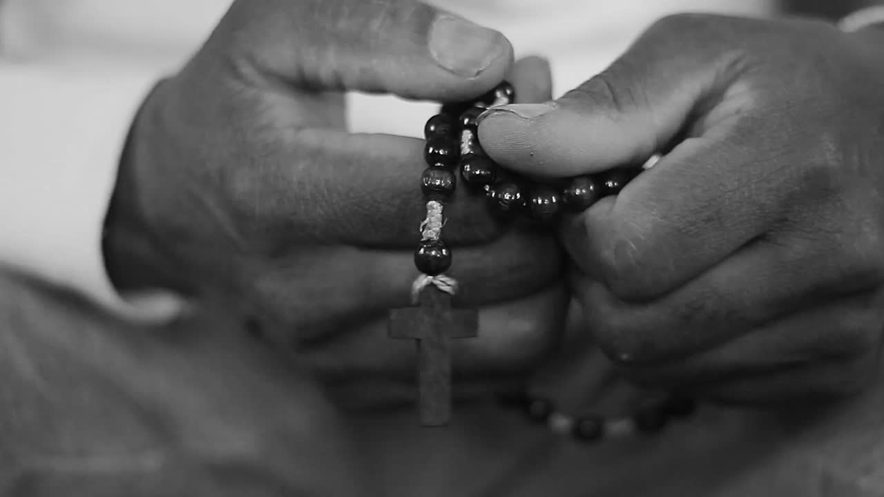 praying to God with hand's together with cross on table with people and black background stock video stock footage