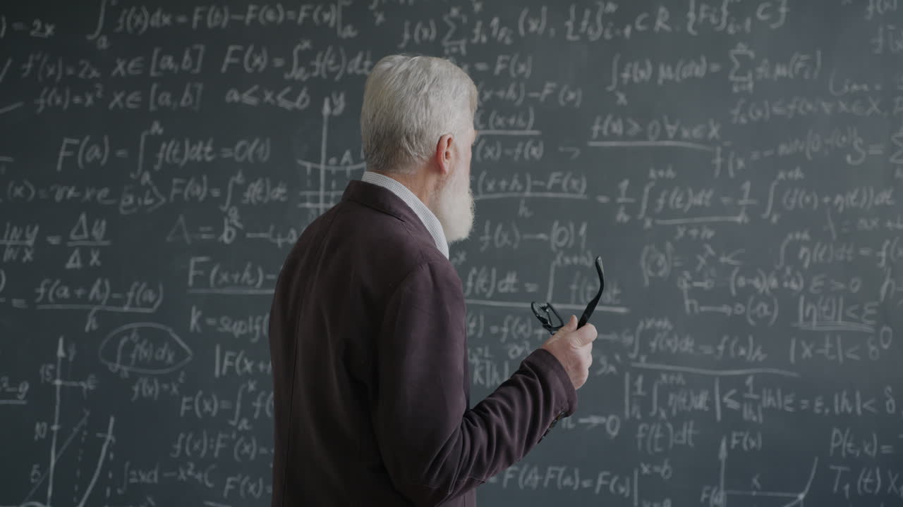 Professor Standing Behind a Blackboard Filled with Math Equations