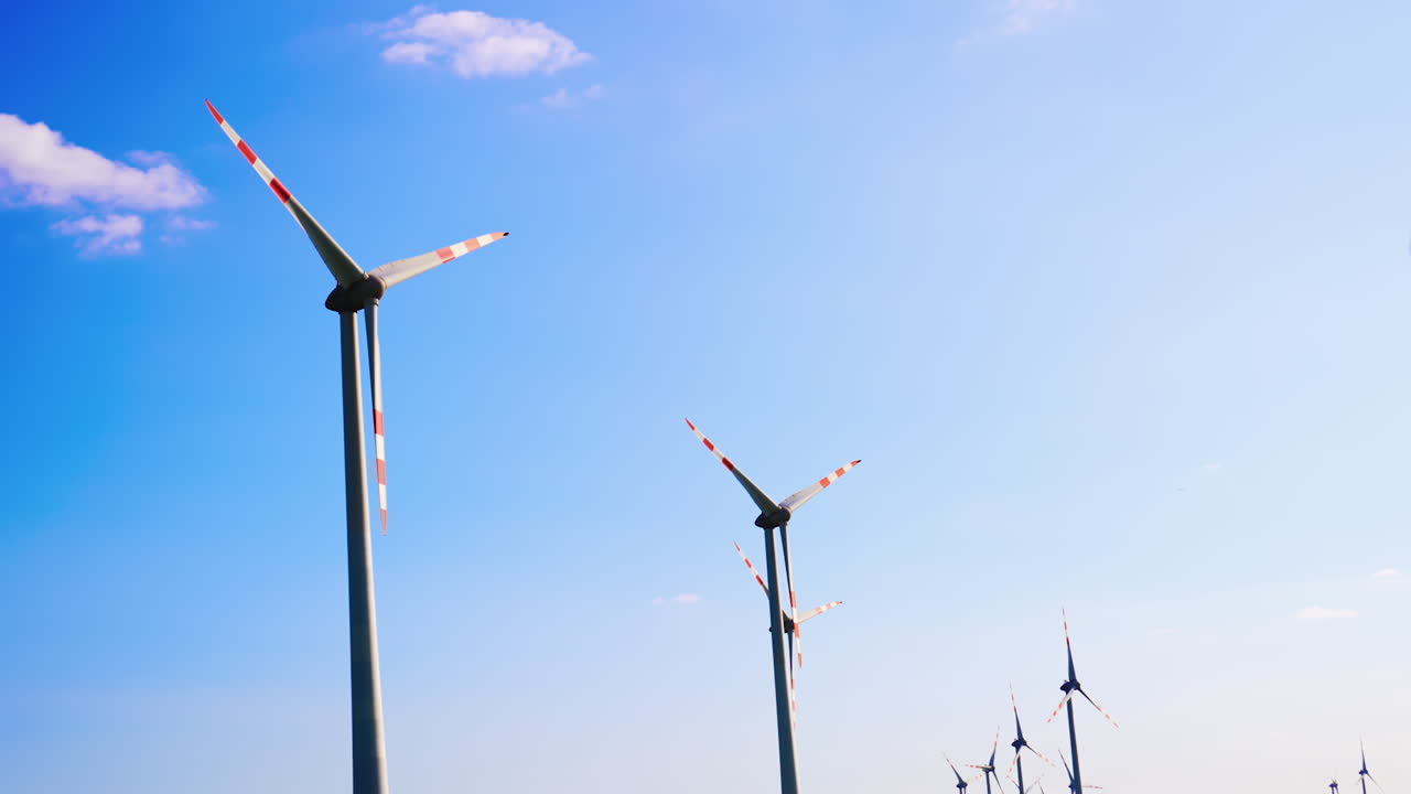 Tops of the wind mills rotating in the wind. Production of sustainable energy. Low angle view