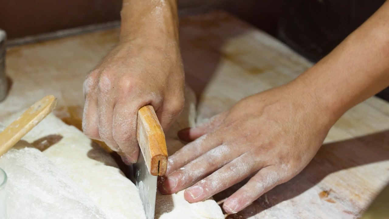 Chef che taglia l'impasto per il tradizionale pane fritto cinese