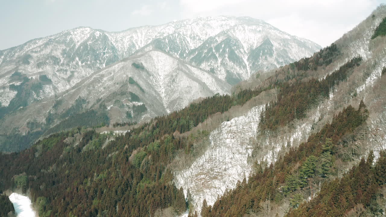 toma cinematográfica de drones de la cordillera cubierta de nieve en un frío y brillante día de invierno en okuhida, japón
