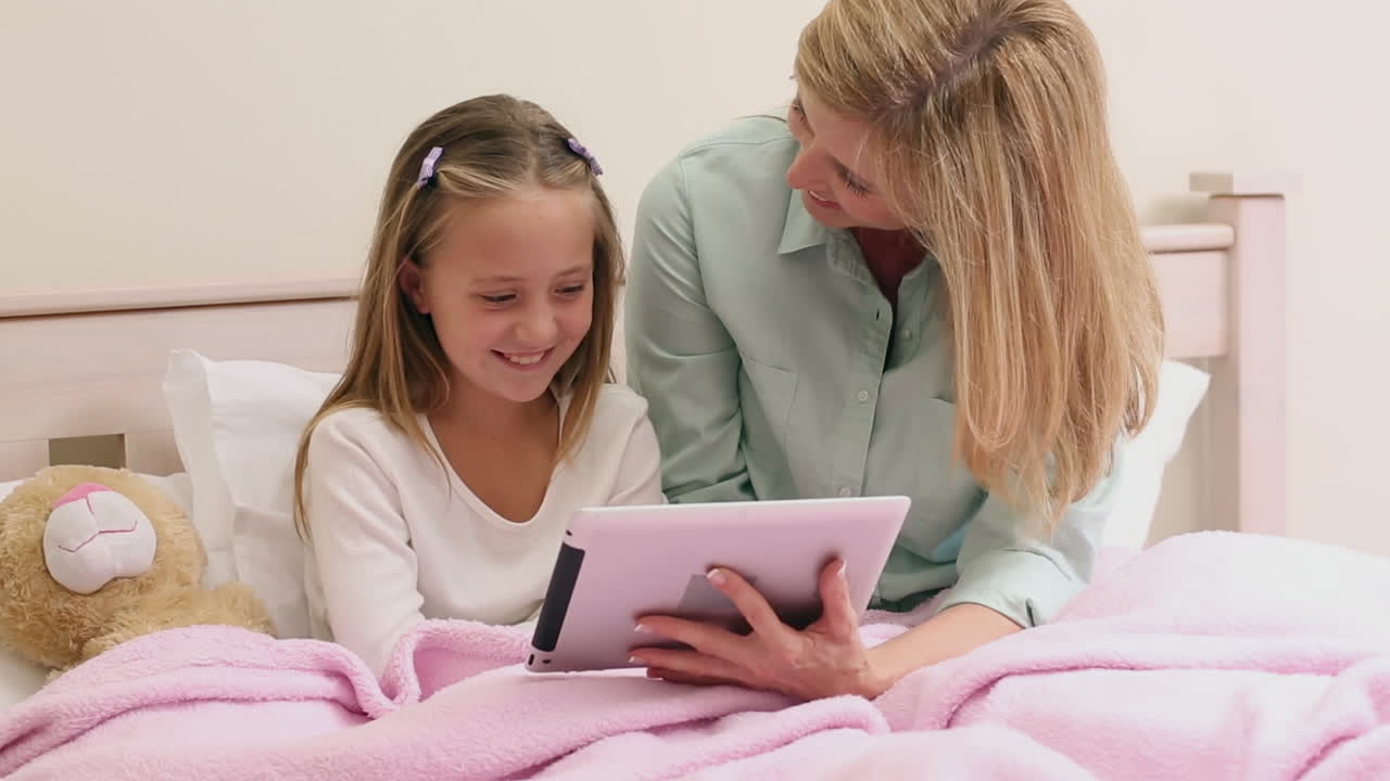 Moeder en dochter die tablet samen op bed gebruiken