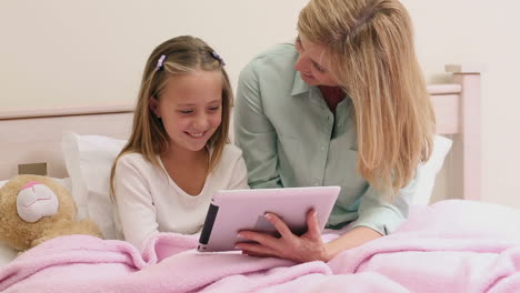madre e hija usando la tableta juntos en la cama