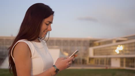 side view of smiling young texting on smartphone outdoor.