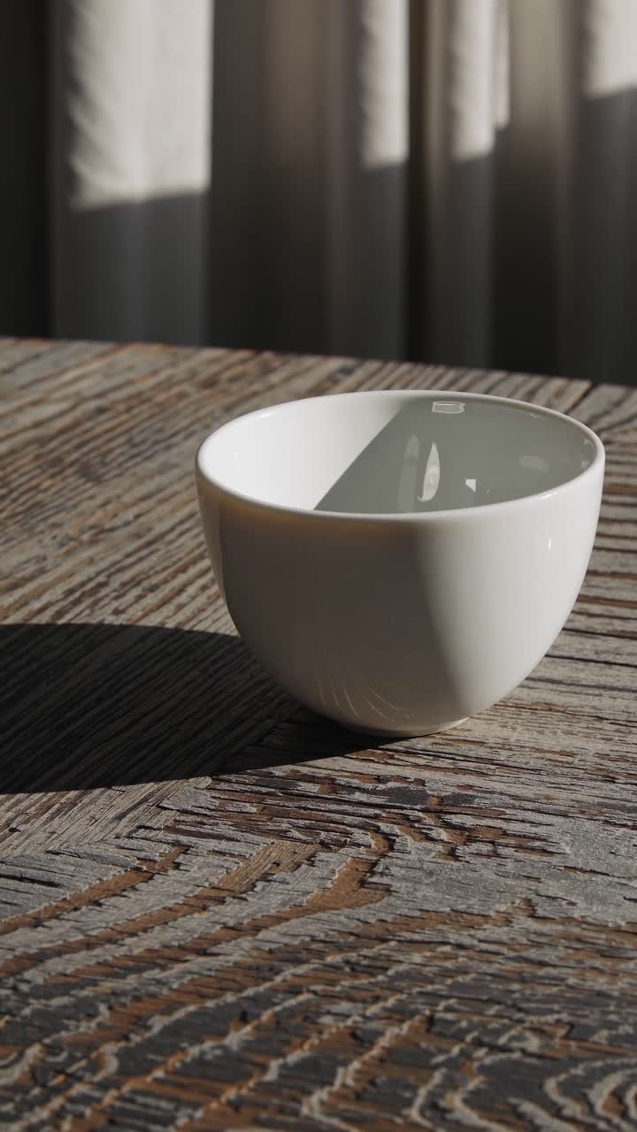 A minimalist video concept featuring a white bowl on a rustic wooden table