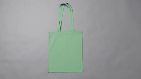primer plano de una bolsa verde sobre un fondo gris, con espacio de copia, cámara lenta