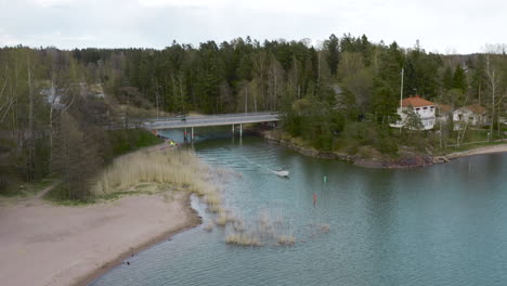 a boat can be seen entering a lake from under bridge as the camera tilts down
