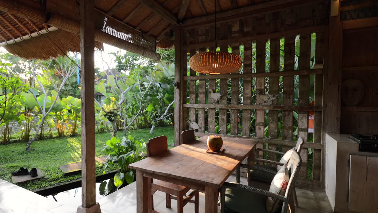 villa tradicional de concepto abierto en bali, indonesia, con destellos solares golpeando la mesa del comedor por la mañana