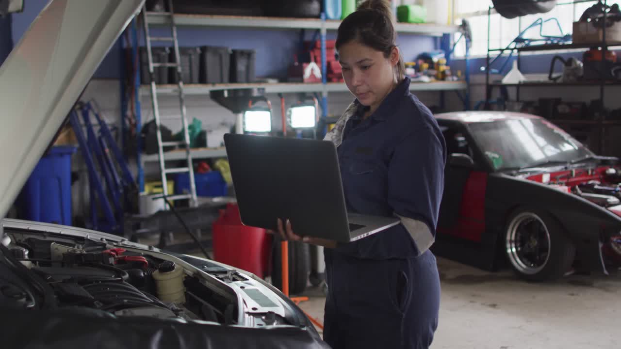 mecánica femenina usando una computadora portátil e inspeccionando el automóvil en una estación de servicio de automóviles