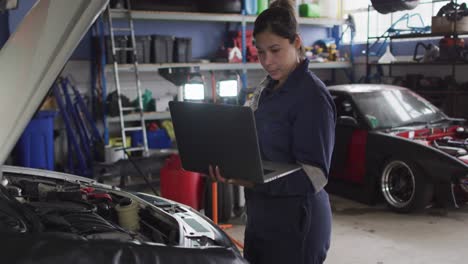 Female-mechanic-using-laptop-and-inspecting-the-car-at-a-car-service-station
