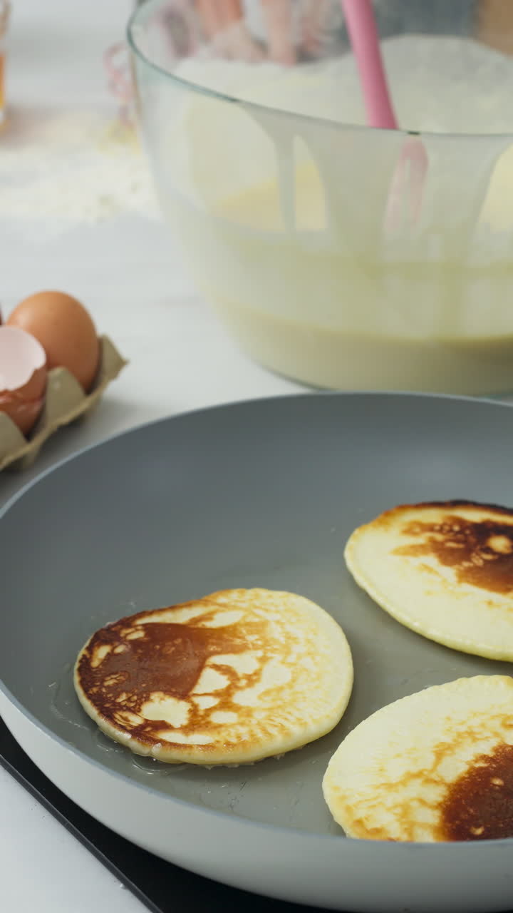 Vertical Of A Hand Flipping Pancake Using A Spatula In A Pan. Close-up Shot