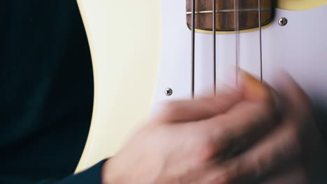 person with yellow pick shows bass guitar play technique