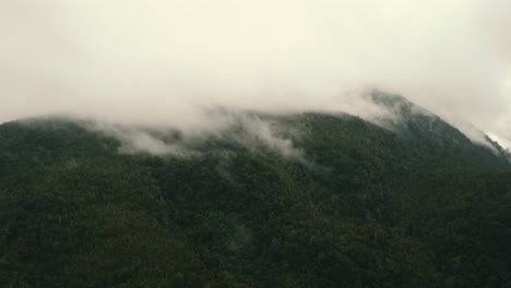 Luftumkreisende-Aufnahme-Von-Wolken-Und-Nebel,-Die-Den-Gipfel-Eines-Berges-Vor-Der-Westküste-In-Neuseeland-Bedecken