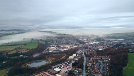 Aerial-footage-of-a-mist-covered-urban-town-of-Heckmondwike-in-Yorkshire-UK,-showing-busy-roads-traffic-and-red-brick-houses