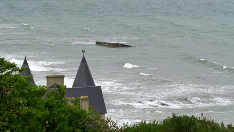 low tide waves sweeping over the phoenix block remnant in mulberry artificial harbour, gold beach, arromanches, normandy, france