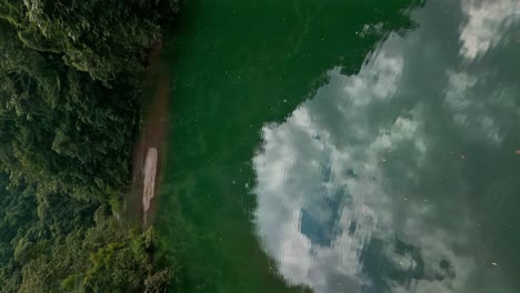 Low-angle-flight-over-green-river-of-bonao-with-Tireo-Dam-in-scenic-area-of-Dominican-Republic---vertical-Forward-Movement