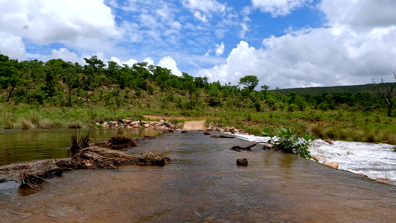 un cruce de puente inundado visto desde un ángulo bajo, mostrando agua corriendo y terreno rocoso