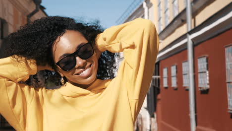 woman in a yellow hoodie smiling outside