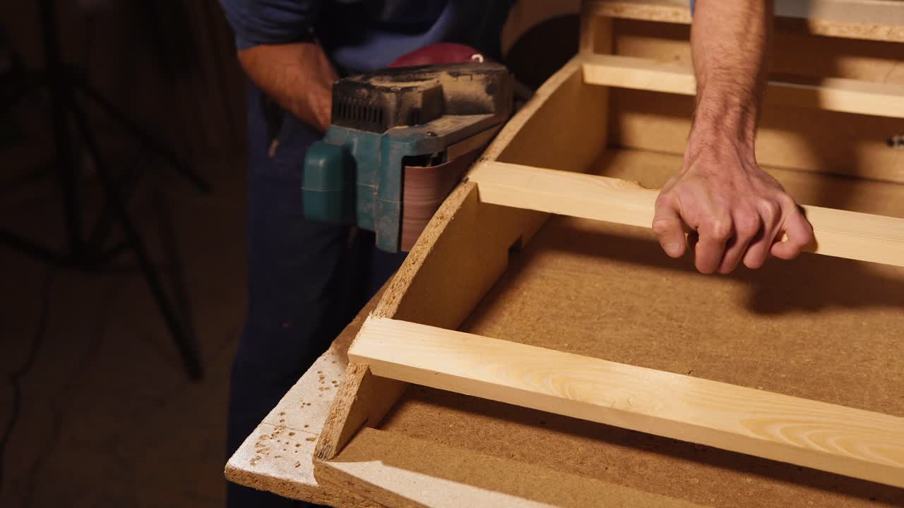 carpintero trabajando con una fresadora de correa en un marco de madera