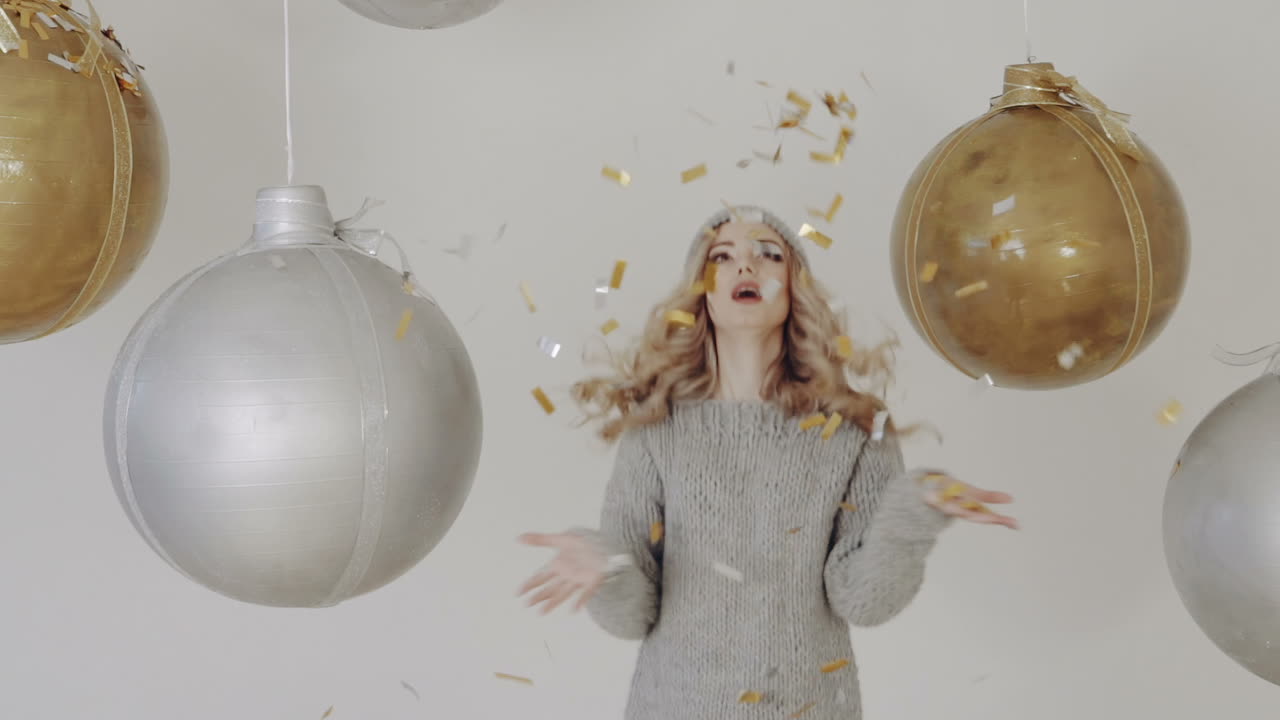 Christmas holiday party. Smiling girl throwing confetti balloons on background
