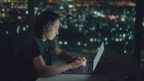 european woman typing text at night illuminated by screen
