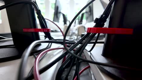 primer plano de la configuración del escritorio de la oficina con cables y cables organizados detrás de los monitores, destacando la gestión tecnológica del lugar de trabajo