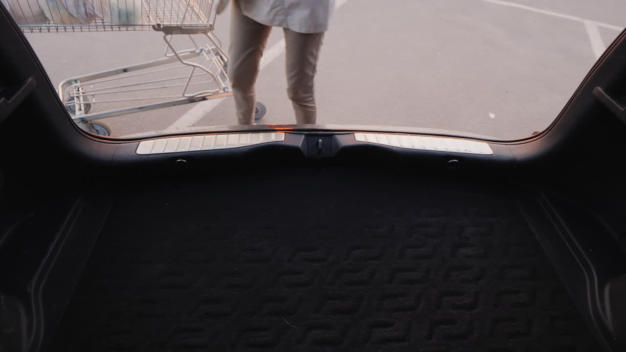 여자는 쇼핑백을 차 트렁크에 넣는다