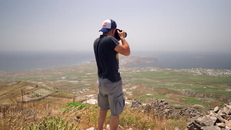 one man takes pictures on a hill of santorini island in greece