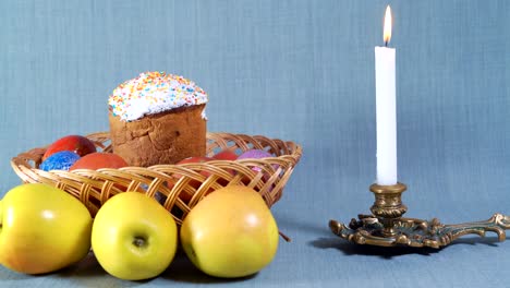 travel cameras, easter arrangement, easter in the wooden basket with painted eggs and apple, near the white candle in the bronze candlestick