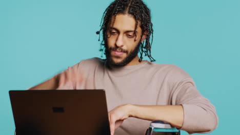 Man composing email, typing on laptop keyboard, studio background