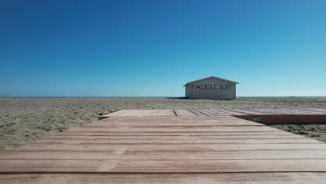 Auf-Dem-Gebäude-Steht-„Paddle-Surf“-Miethaus,-Horizontaler-Rahmen,-Bodensand-Und-Blauer-Himmel