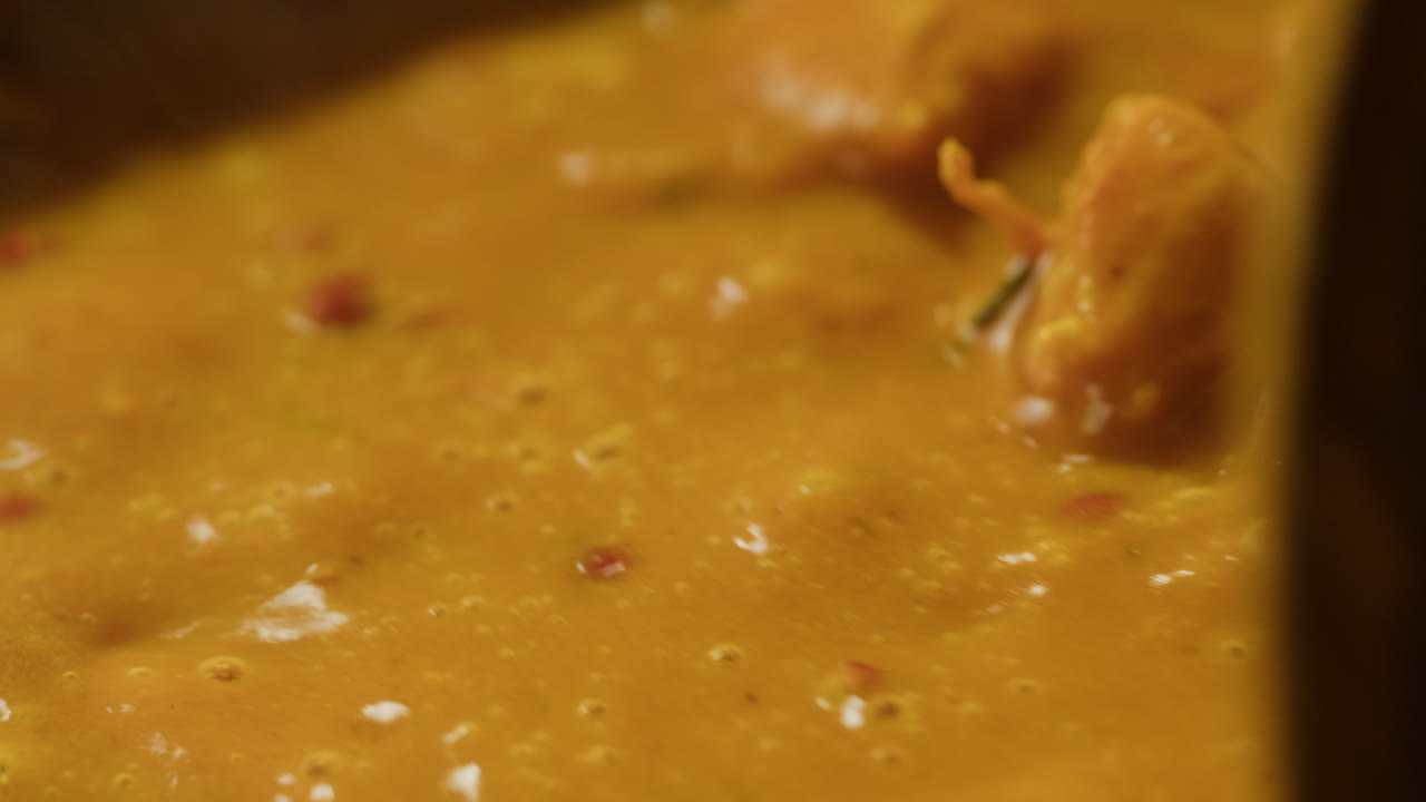 Yellow boiling sauce on pan close-up. Asian cuisine concept. Curry is a dish with a sauce seasoned with spices. Curries may contain fish, meat, poultry, or shellfish, either alone or in combination with vegetables. Others are vegetarian.
