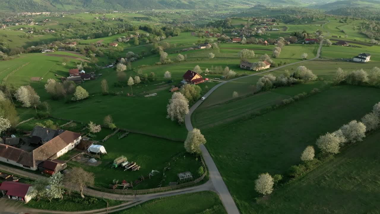 Ilmakuva ylhäältäpäin pienestä maaseutukylästä Keski-Slovakiassa, jota ympäröi rehevä vehreys ja kukkivat päärynäpuut keväällä.