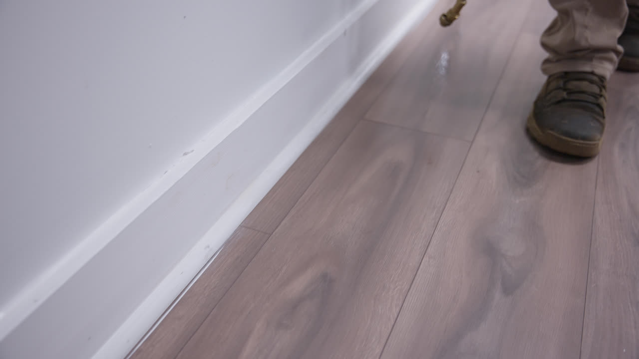 Pest control treatment applied carefully along white office wall baseboards