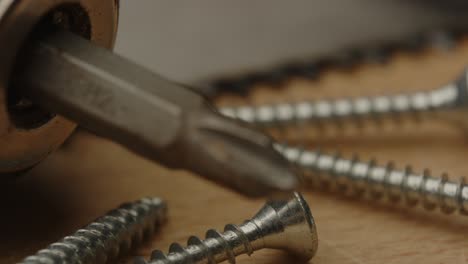 macro focus rack from drill bit of electronic screw driver to metal screws and saw on a wooden surface