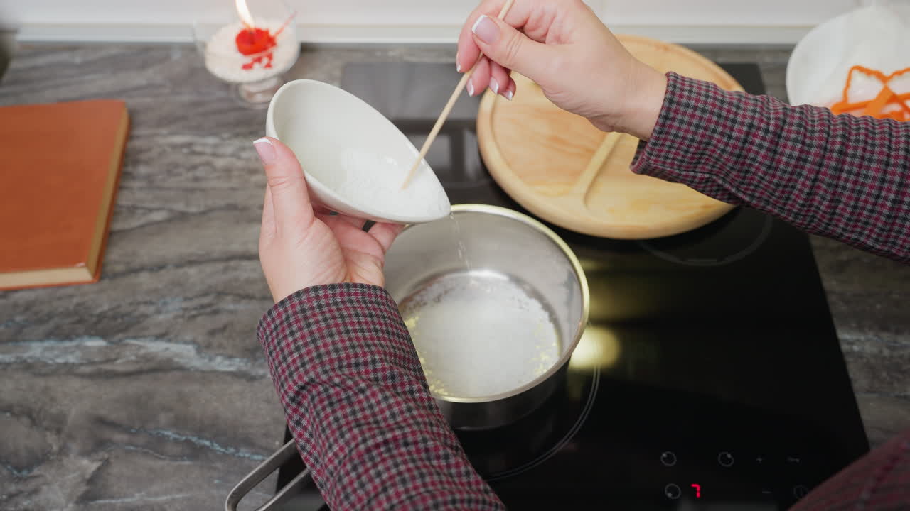 현대 주방에서 요리 또는 디저트 준비를 위해 재료를 준비하는, 거의 불타는 스토브에서 비에 설탕을 는 사람의 위에서 아래로 볼 수 있습니다.