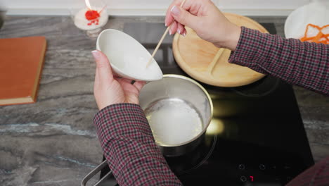 vista de arriba hacia abajo de una persona vertiendo azúcar en la olla en la estufa casi quemándose, preparando ingredientes para cocinar o preparar postres en la cocina moderna