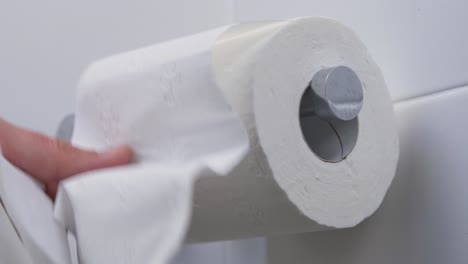 close-up slow motion shot of pulling toilet roll tissue paper on toilet holder bathroom people personal hygiene loo 4k