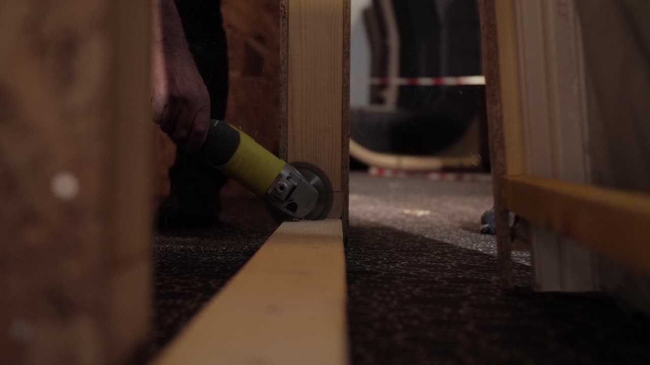 low angle shot of a worker using an angle grinder to cut through a wooden beam